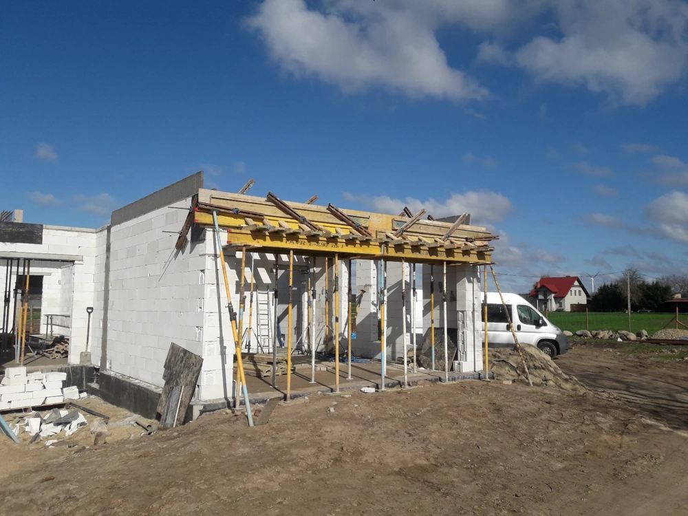 Dom w stanie surowym otwartym z murowanymi ścianami z bloczków i rusztowaniami do szalowania stropu