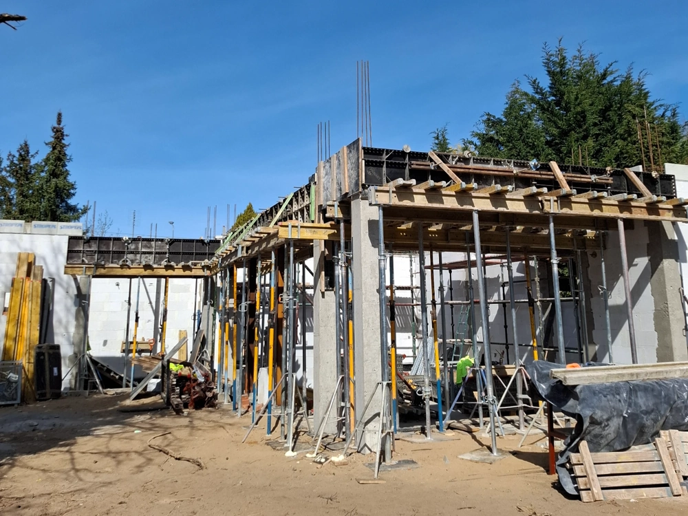 Plac budowy stanu surowego otwartego z betonowymi słupami, szalunkami i rusztowaniem