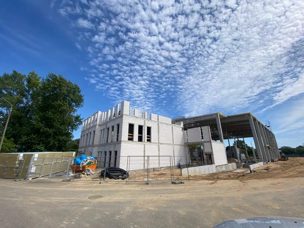 Dwukondygnacyjny budynek w stanie surowym otwartym z murowanymi ścianami i ogrodzeniem placu budowy