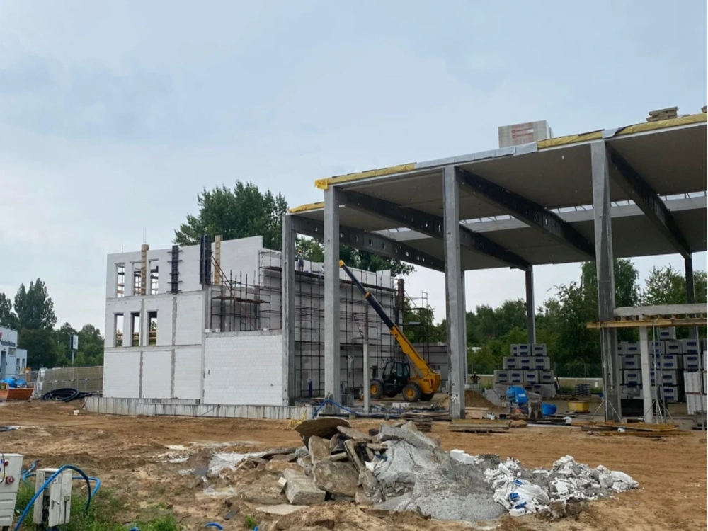 Stan surowy otwarty budynku z murowanymi ścianami i żelbetowymi słupami oraz sprzętem na placu