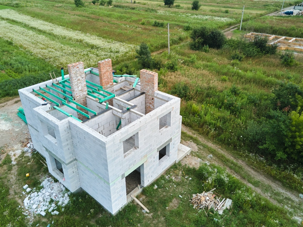 Dwukondygnacyjny budynek w stanie surowym otwartym z murowanymi ścianami i belkami stropowymi