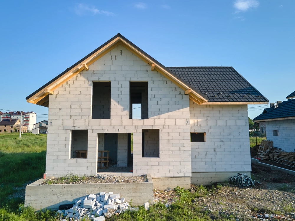 Dom jednorodzinny w stanie surowym otwartym z murowanymi ścianami z bloczków i konstrukcją dachu
