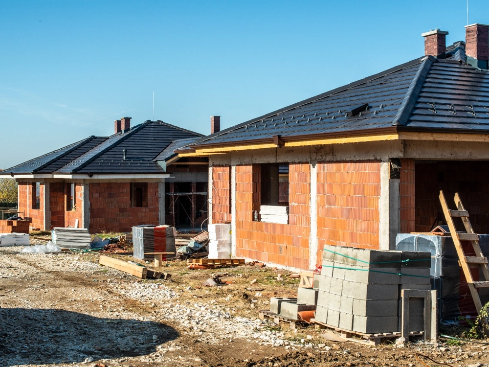 Stan surowy otwarty domów z murowanymi ścianami i dachami, plac budowy z materiałami