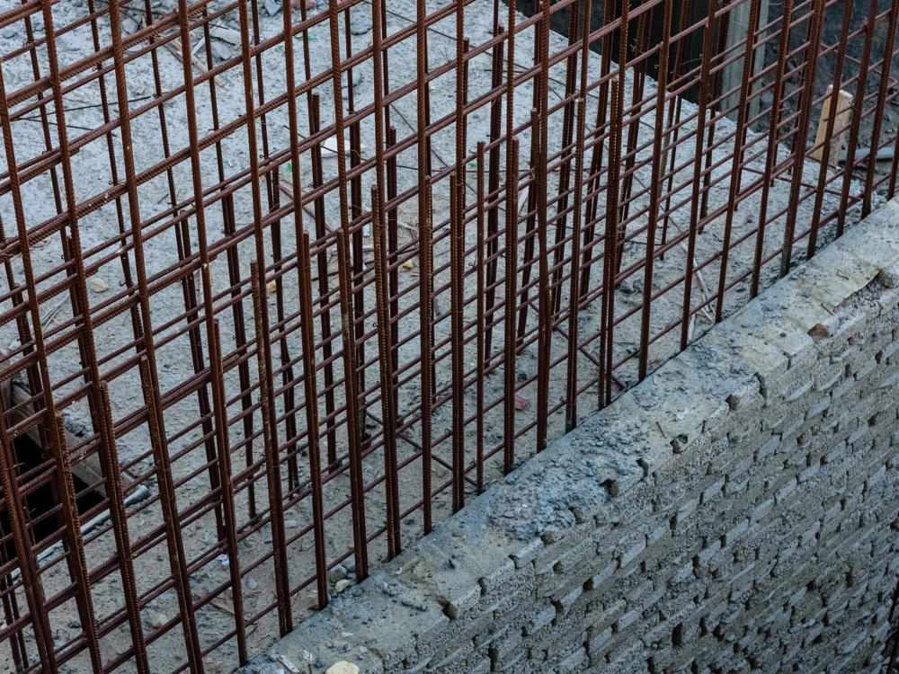 Zbrojenie fundamentów: pionowa siatka prętów zbrojeniowych przygotowana na wykopie