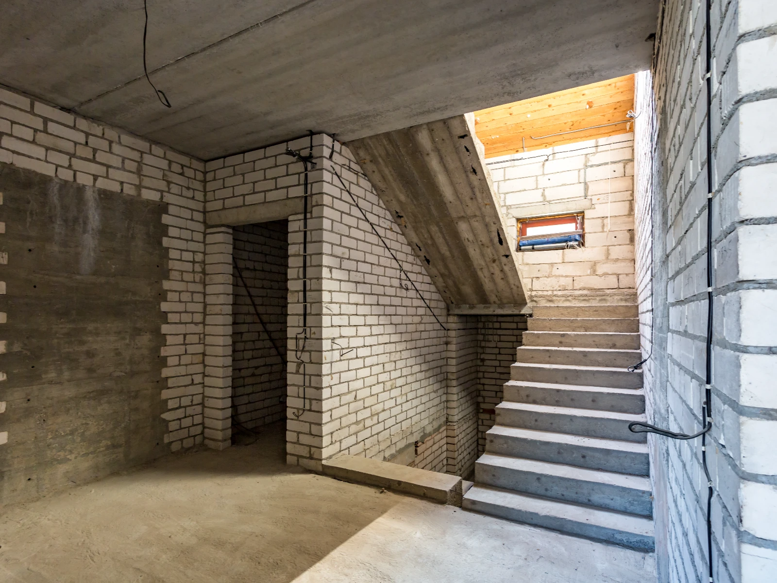 Schody betonowe w nieotynkowanym wnętrzu z murowanymi ścianami