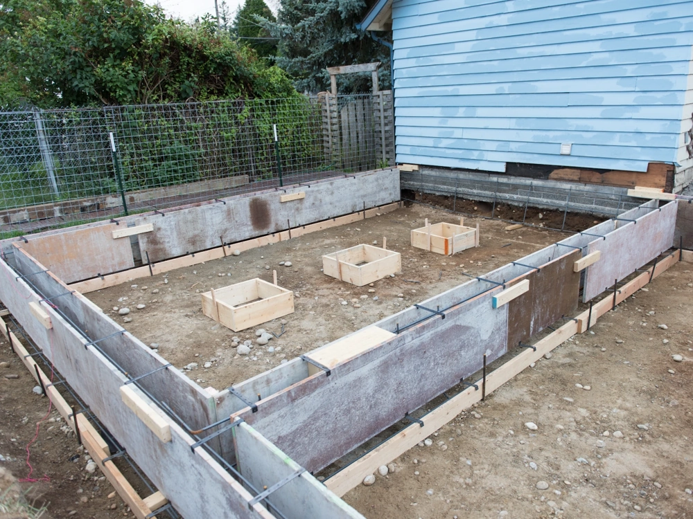 Przygotowanie szalunków drewnianych wraz z zbrojeniem pod ławy fundamentowe obok istniejącego budynku