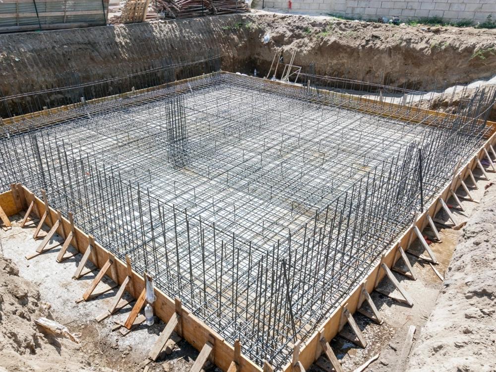 Zbrojenie płyty fundamentowej w wykopie – gęsta siatka prętów zbrojeniowych i szalunki