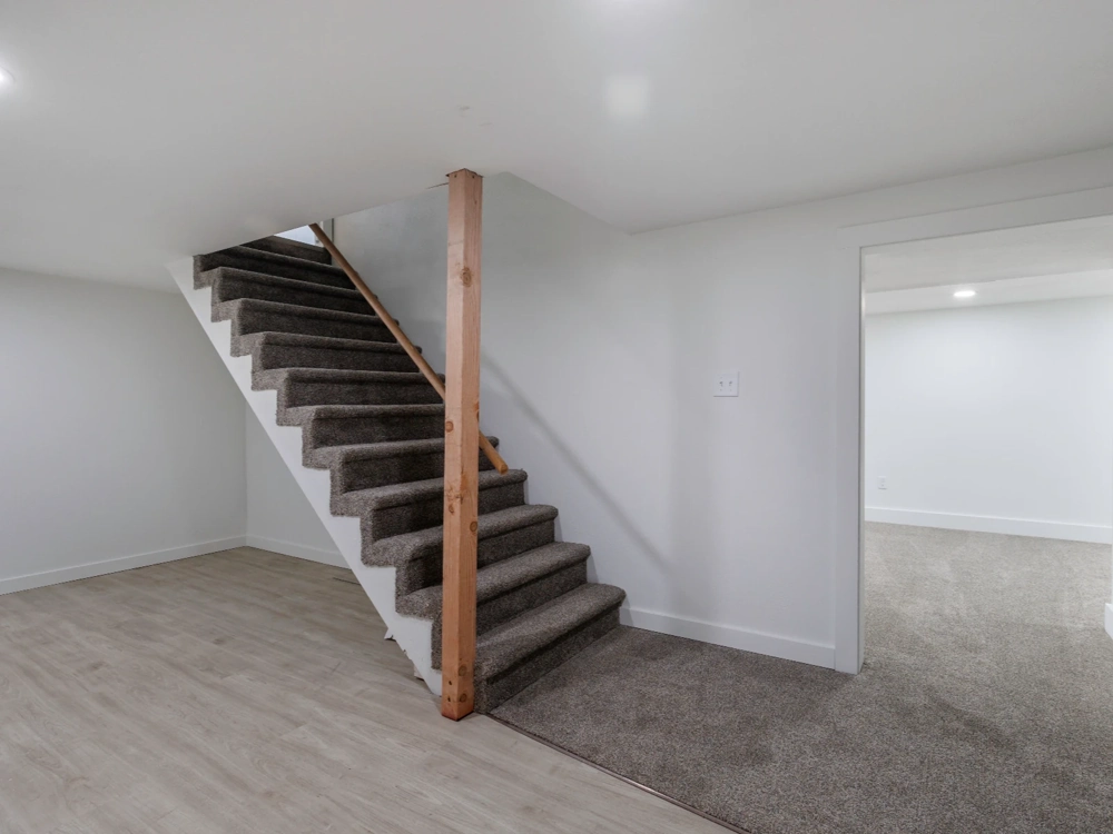 Schody betonowe wykończone wykładziną z drewnianym słupem we wnętrzu piwnicy