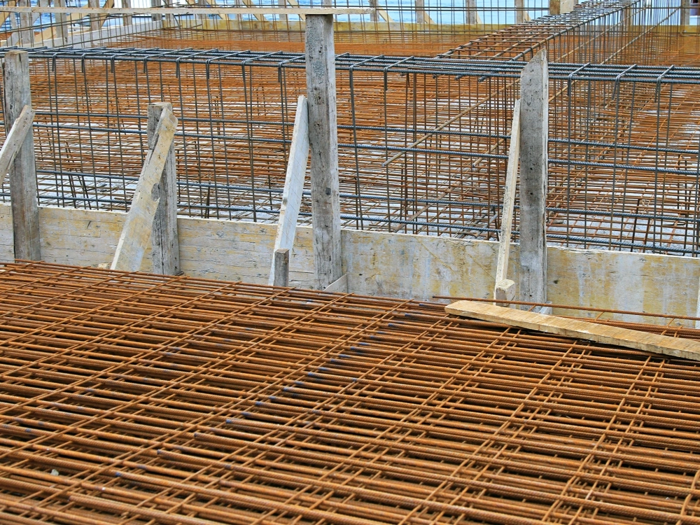 Zbrojenie fundamentów – siatka stalowych prętów ułożona na deskowaniu przed wylaniem płyty fundamentowej