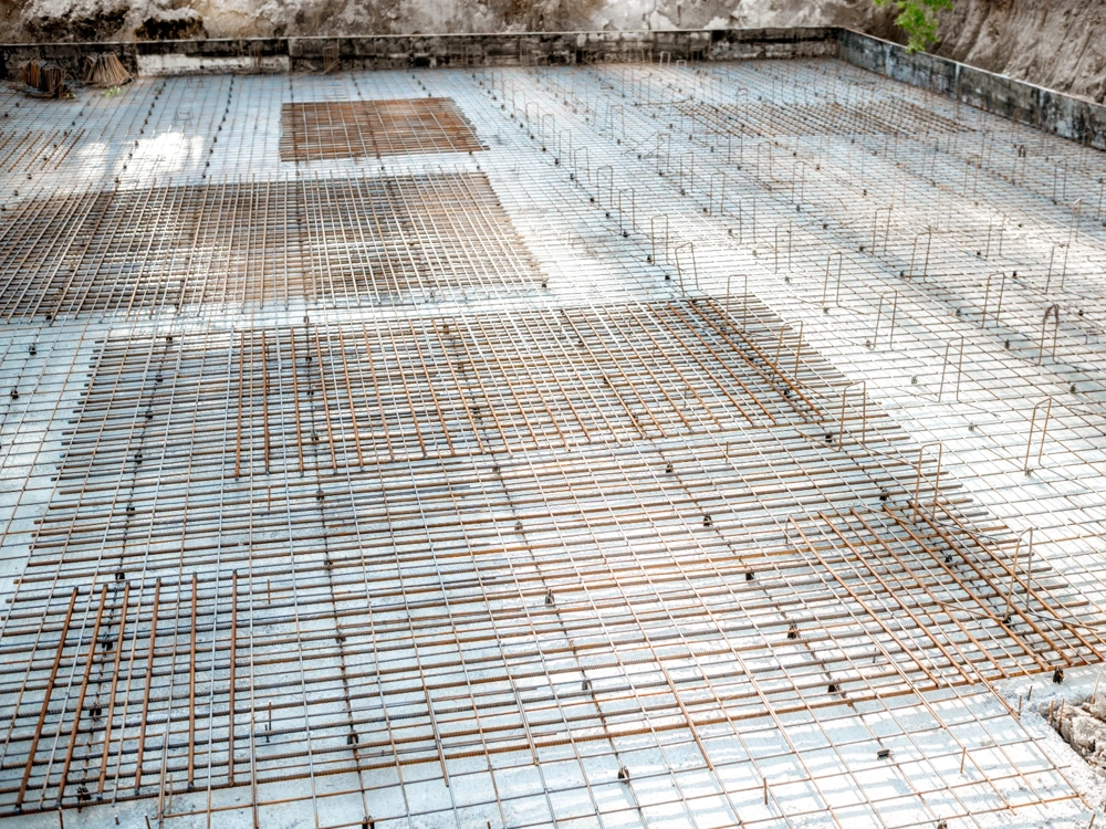 Zbrojenie płyty fundamentowej z siatką stalowych prętów w przygotowanym wykopie