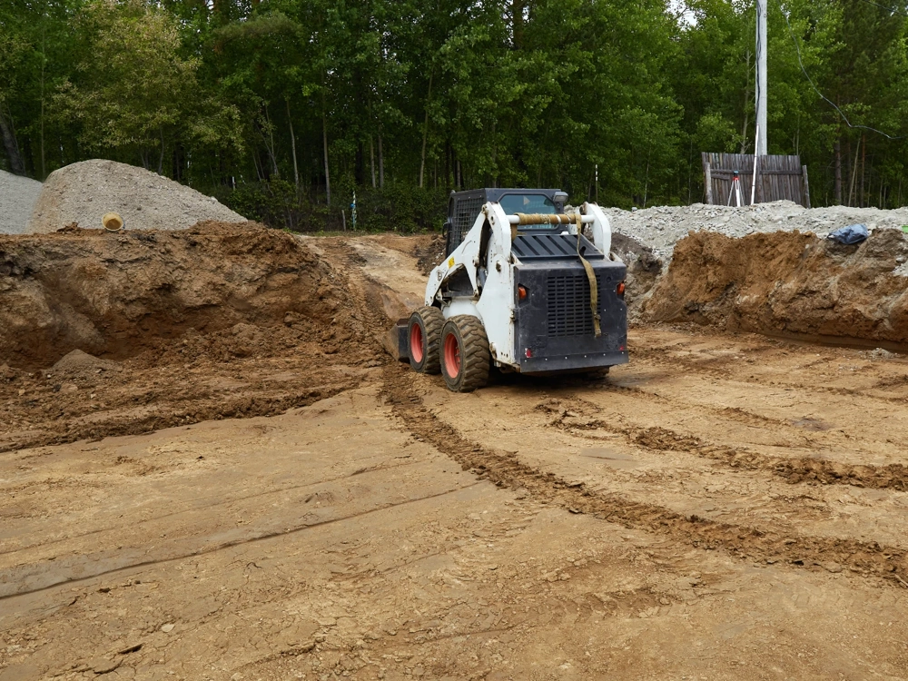 Miniładowarka równająca teren w wykopie Prace ziemne