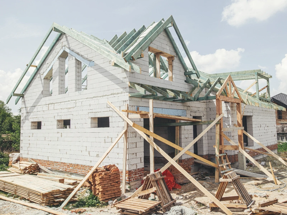 Budynek z murowanymi ścianami i drewnianą więźbą dachową na placu budowy Stan surowy otwarty